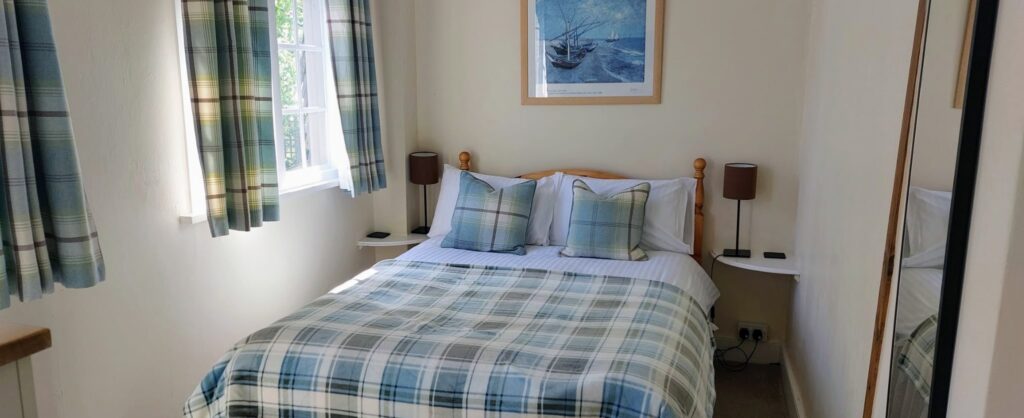 A room with a double bed with checked blanket